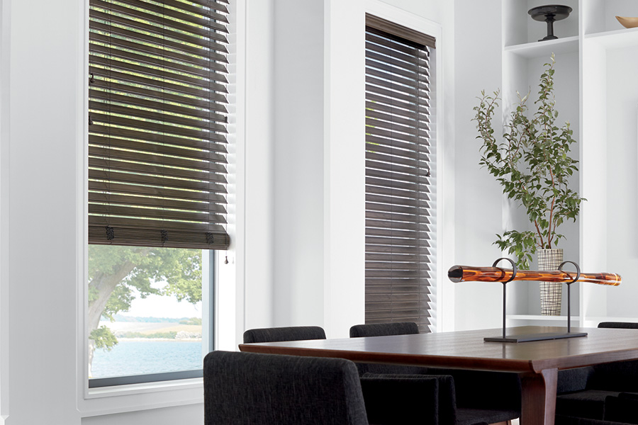 Dark faux wood blinds in three windows. A large dining room with modern decor.